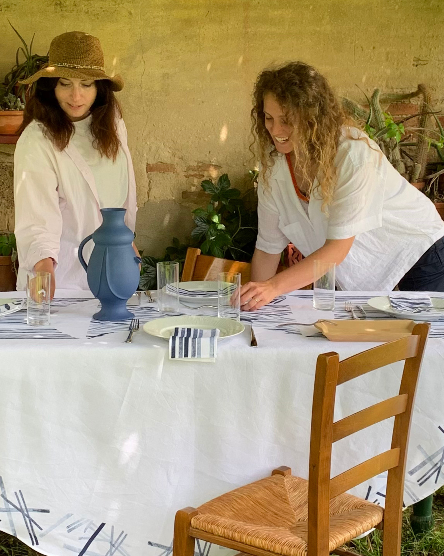 Rustic table setting in Tuscany featuring a handcrafted tablecloth printed with the rust dye technique from Emilia Romagna.