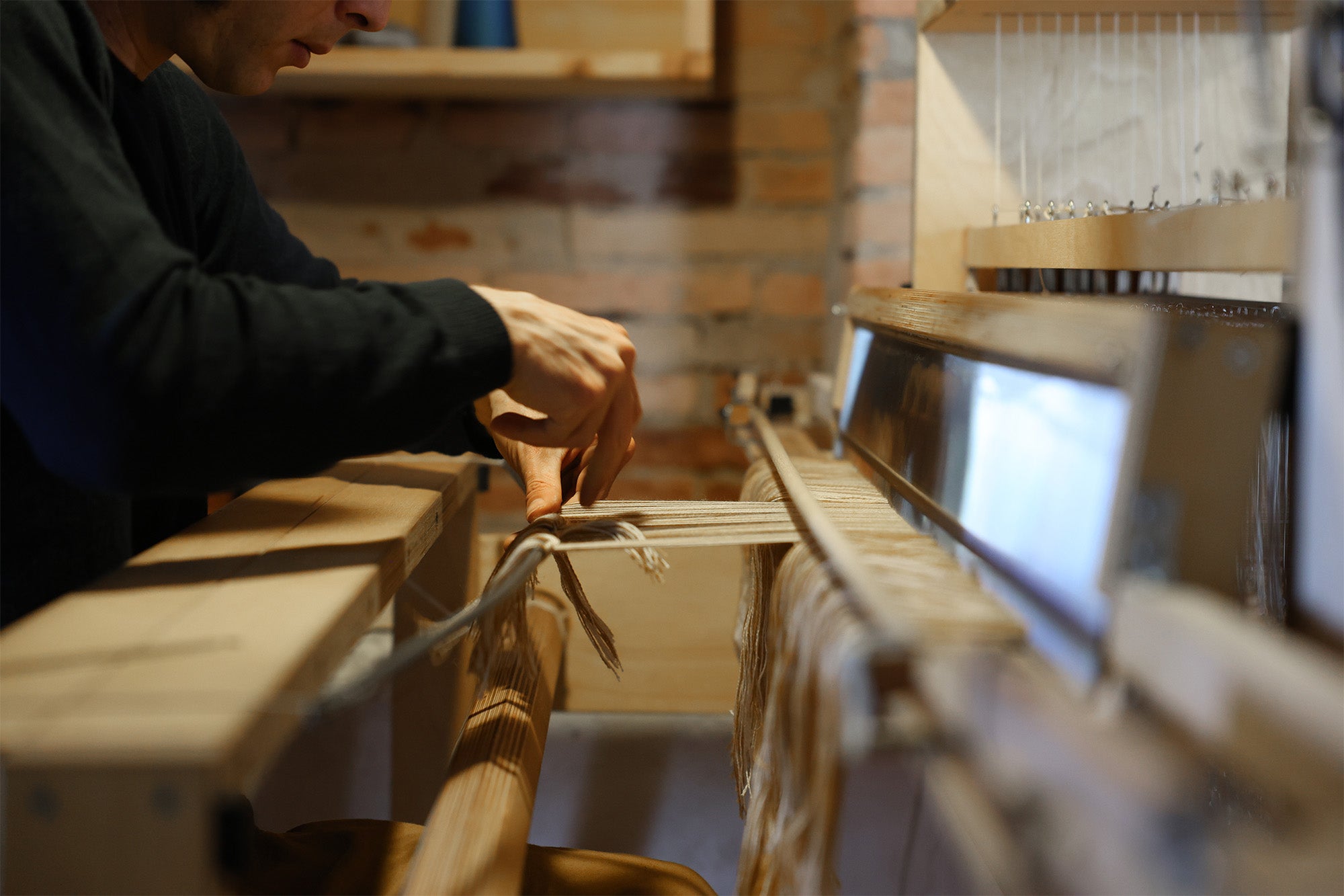 Hands weaving on a traditional wooden loom in Tuscany, preserving local textile craftsmanship.